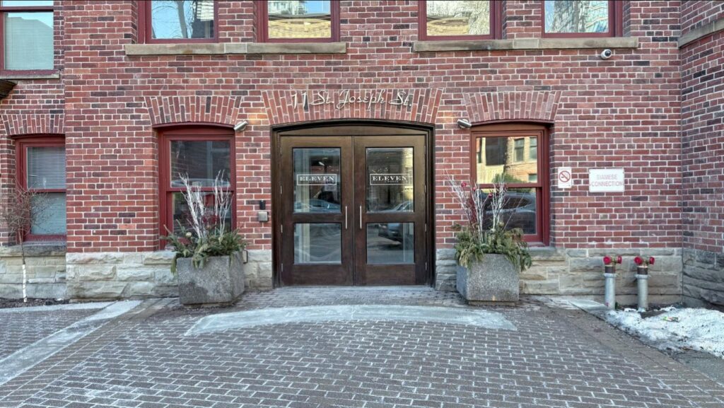 Front entrance of Eleven Residences at 11 St Joseph St, featuring elegant double doors and a well-maintained exterior in the Bay Street Corridor.