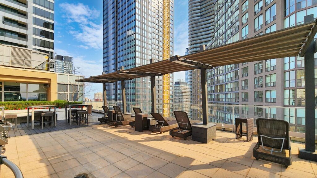 Covered lounge chairs on the rooftop of Eleven Residences, 11 St Joseph St, offering shaded relaxation with views over downtown Toronto.