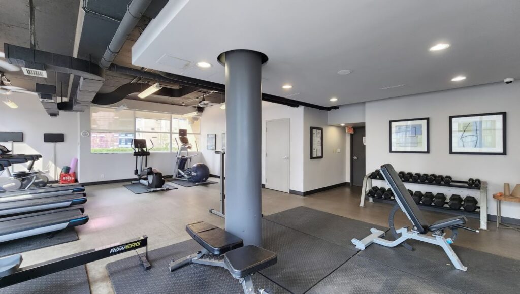 Fitness centre at Eleven Residences, 11 St Joseph St, featuring a range of cardio and strength-training equipment in a bright, well-maintained space.
