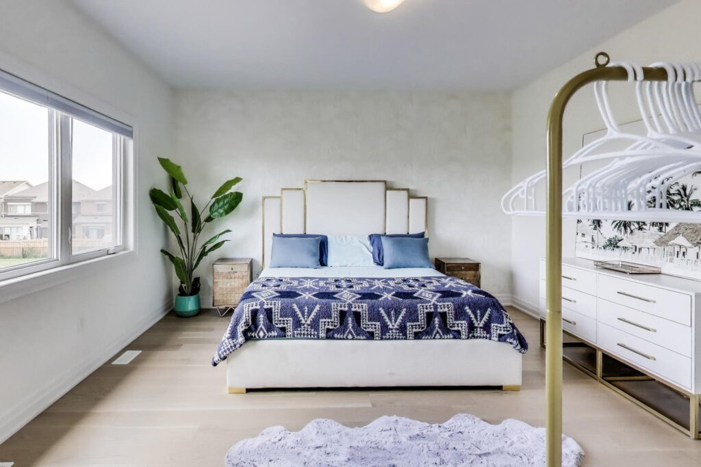 Primary bedroom with large window overlooking backyard and blue bedding—59 Maskells Cres.