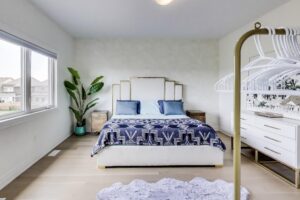 Primary bedroom with large window overlooking backyard and blue bedding—59 Maskells Cres.