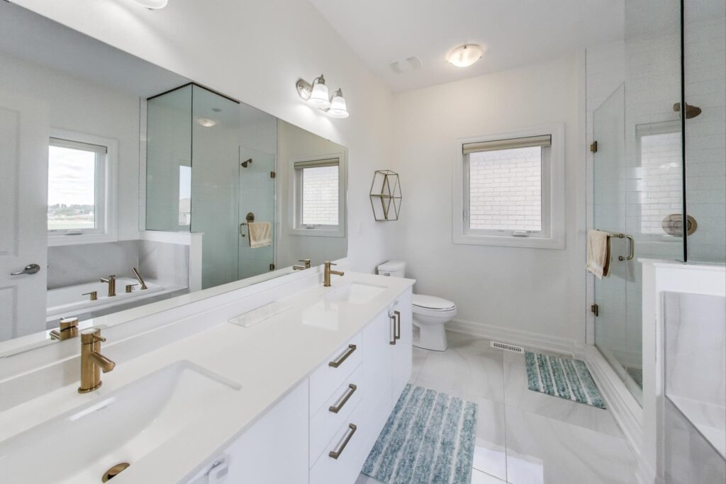 Primary ensuite at 59 Maskells Cres—double vanity with brass faucets, glass shower and soaker tub.